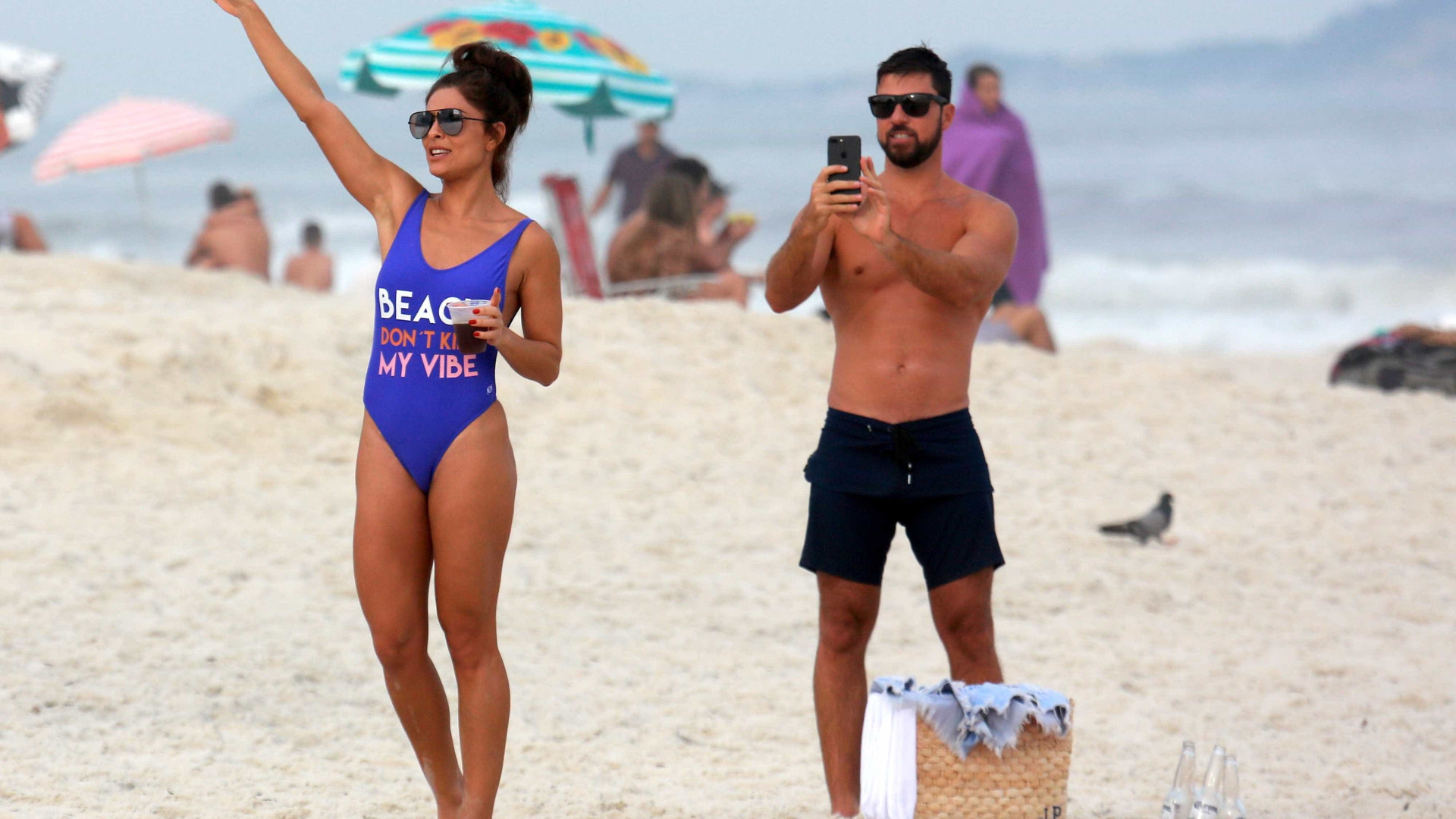 Juliana Paes curte praia com maiô cavado e leva "mão boba" do marido