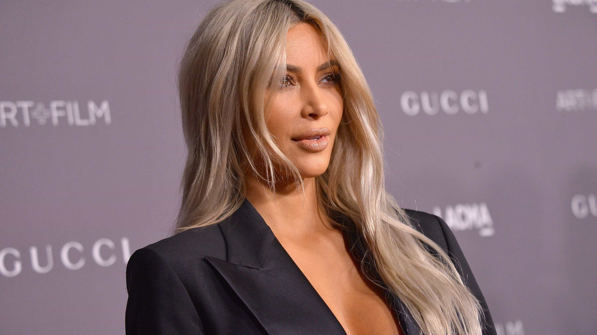 Kim Kardashian vai a evento com blazer aberto e sem sutiã