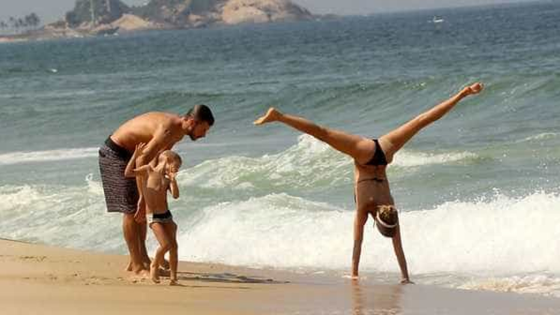 Fernanda Lima faz acrobacia em praia com família