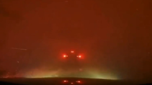 Carro percorre estrada rodeada por incêndio de grande dimensão no Canadá